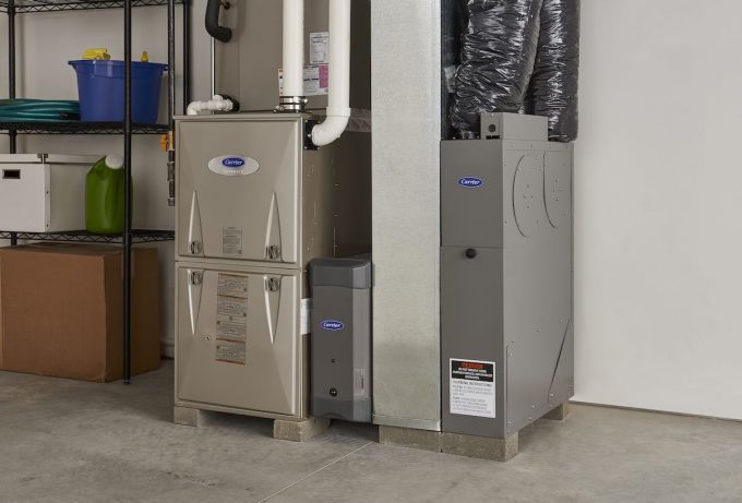 Technician installing a modern furnace in a Sand Springs, OK residential utility room during winter